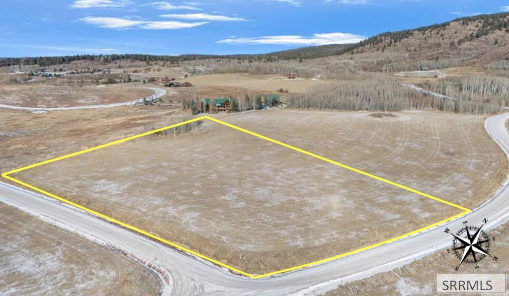Aerial of the parcel with lot boundary outlined in yellow, Teton range visible on the horizon.